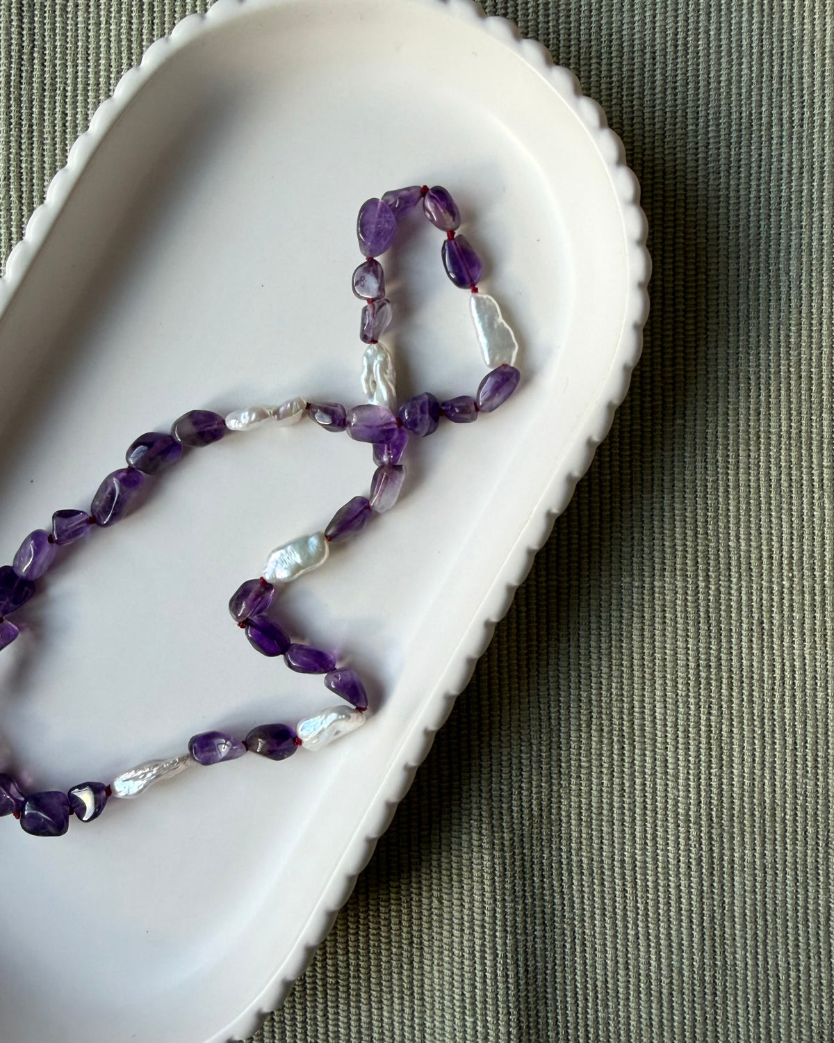 Amethyst nugget beads and long biwa pearls silk knotted and shown on a pale dish
